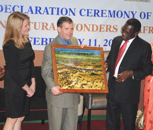 Prime Minister Mizengo Pinda (right) presenting a photograph depicting wildebeest migration in the Serengeti to the President and Founder of Seven Wonders, Dr. Philip Imler at the Mount Meru Hotel on February 11. Left is Dr. Imler's wife, Nancy Imler. (Photograph by Filbert Rweyemamu)